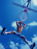 Low Angle View of a Young Man Slam Dunking a Basketball