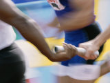 Mid Section View of Runners Exchanging Baton at a Relay Race