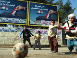 Iraqi Boys Play Soccer Below the Poster Reading 