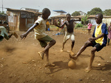 Young Children Play Soccer on a Dirt Pitch by the Side of Railway Tracks