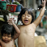 Filipino Children React as They Get a Shower Outside Their Homes Photographic Print