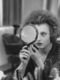Actress Hanna Schygulla Looking in Hand Mirror While Applying Makeup