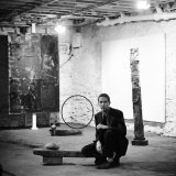 Robert Rauschenberg Sitting on His Sculpture in Studio, Among Other Paintings and Sculptures