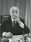 Portrait of RCA Chairman David Sarnoff Sitting at Desk in His Office, Smoking a Cigar