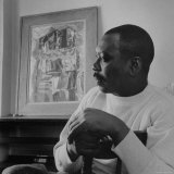 Jacob Lawrence Sitting in Front of One of His Paintings