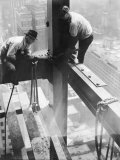 Workers balancing on steel beam above streets during construction of the Manhattan Company Building Photographic Print