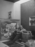 Buy Architect Le Corbusier Sitting in Chair with Book in Hands, Glasses Perched on His Forehead at AllPosters.com