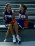 Two Cheerleaders Sitting with Pom-Poms
