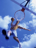 Low Angle View of a Young Man Slam Dunking a Basketball