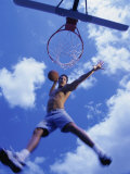 Low Angle View of a Young Man Slam Dunking a Basketball