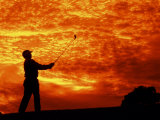 Man Swinging Golf Club at Sunset