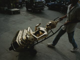 A Golden Buddha Statue is Wheeled by Handtruck on a Thai Street