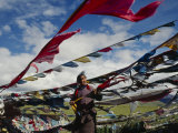 A Tibetan Pilgrim Hoists Prayer Flags Over a Mountain Pass in Tibet