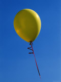 Single Yellow Balloon on a Red Ribbon with a Blue Sky