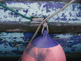 A Colorful Buoy Hangs from Ropes off the Side of a Boat