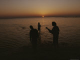 Buy Several People are Silhouetted Standing in Shallow Water at Sunset at AllPosters.com