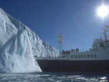 An Expedition Ship Nears a Waterfall Cascading from an Icecap
