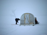 His Fishing Hole Marked by a Branch, an Ice Fisherman Waits for His Next Victim to Take the Bait