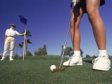 Golfer Putting While Other Person Holds Flag