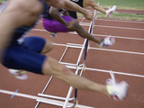 Side Profile of Three People Jumping a Hurdle