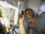 Buy Low Angle View of a Young Man Checking the Plumbing with a Flashlight at AllPosters.com