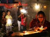 Buy A Woman Lights Earthen Lamps as Children Ignite Firecrackers in New Delhi at AllPosters.com