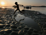 A Boy Plays on the Banks of the River Brahmaputra in Gauhati, India, Friday, October 27, 2006