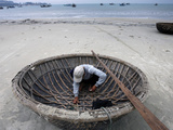 Buy A Vietnamese Fisherman Does Repairs on His Basket Boat on a Beach at AllPosters.com