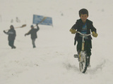 Buy A Young Afghan Boy Rides His Bicycle on a Snow Covered Street at AllPosters.com