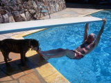 Sen. Barry Goldwater Hanging Underneath Diving Board in Swimming Pool as Dog Licks His Toes