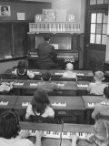 Elementary School Music Teacher Playing F-Major Chord on Piano, Keys Light up on Plastic Keyboard
