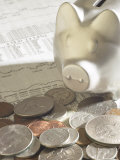 Silver Piggy Bank on Top of Pile of American Coins and Stock Market Report