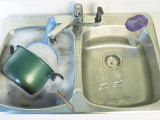 Dirty Pots and Wineglasses Soaking in Soapy Water of Kitchen Sink