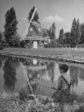 Boy Fishing in a River Reflecting a Dutch Windmill