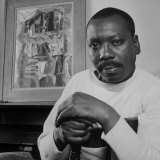 Artist Jacob Lawrence Sitting in Front of One of His Paintings