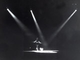 Skater Dancing on Ice, Illuminated by Three Spotlights on Her Back