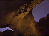 Stars trace arcs across the sky above Death Valley's Natural Bridge Photographic Print