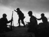 Four Soldiers with Helmets and Rifles Moving on Crest of Ridge, Patroling at Night