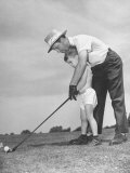 Father Teaching His Small Son How to Play Golf