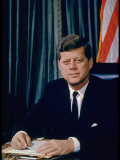Buy Pres. John F. Kennedy Sitting at His Desk, with Flag in Bkgrd at AllPosters.com