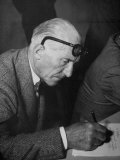 Buy Swiss Architect Le Corbusier Leaning Down to Write with His Glasses Pushed Back on His Forehead at AllPosters.com