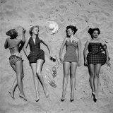 Four Models Showing Off the Latest Bathing Suit Fashions While Lying on a Sandy Florida Beach