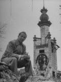 Henry Koerner Sitting on Ground Beside Exotic Tower