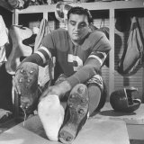 Football Player Ben Agajanian Putting on Football Cleats