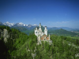 Neuschwanstein Castle on a Wooded Hill with Mountains in the Background, in Bavaria, Germany
