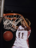 Female Basketball Player Dunking a Ball Through the Hoop