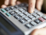 Close-up View of Female Hands Using a Calculator