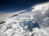 View of Clouds, Airplane Wing and the Sun from Window