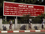 Burmese Walking Past a Govenment Sign Espousing their Desires