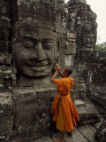 Young Buddhist Monk Prays at a Relief Statue of Buddha